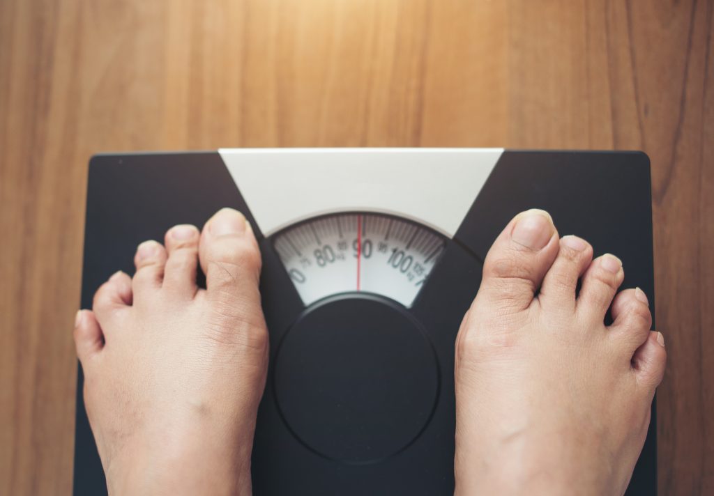 Woman Feet Standing On Weight Scale On Wooden Background